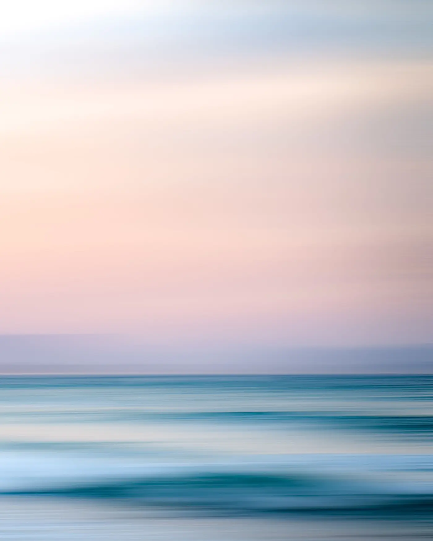 Calm pastel ocean under a soft pink sky